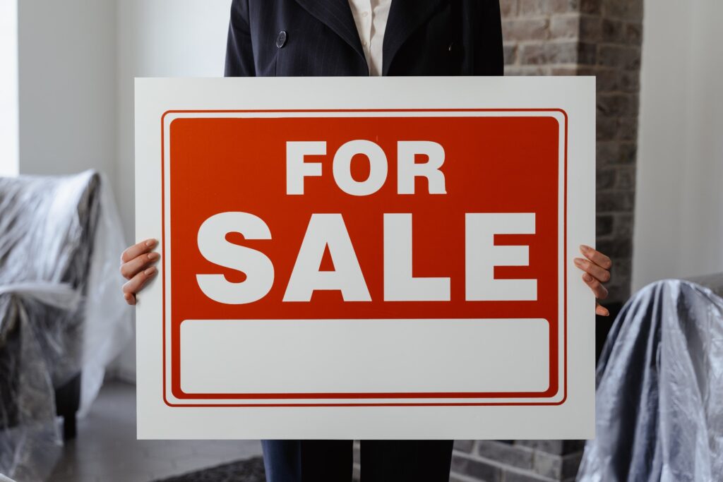 someone holding a for sale sign