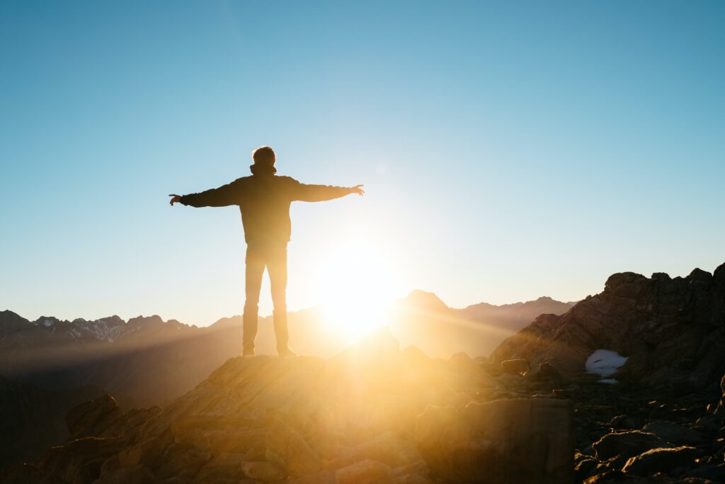 Free man spreading his arms on a mountain at sunrise