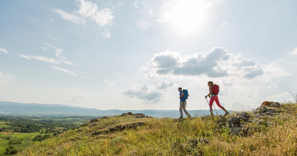 man and woman exploring a mountain with a vast scenic view in the background